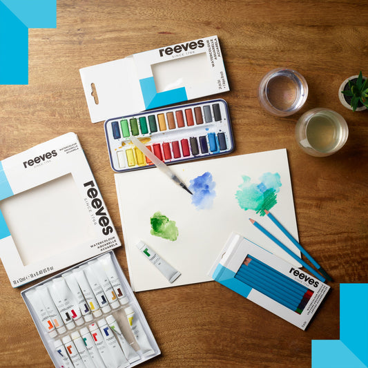 watercolour paint, pencil set, paper and other art materials arranged on a table